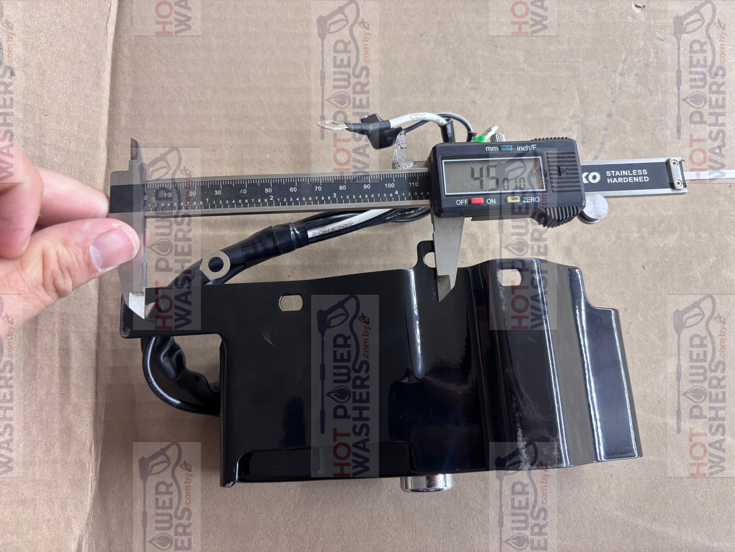 Digital caliper measuring the dimensions of the Lifan ignition switch box on a cardboard surface