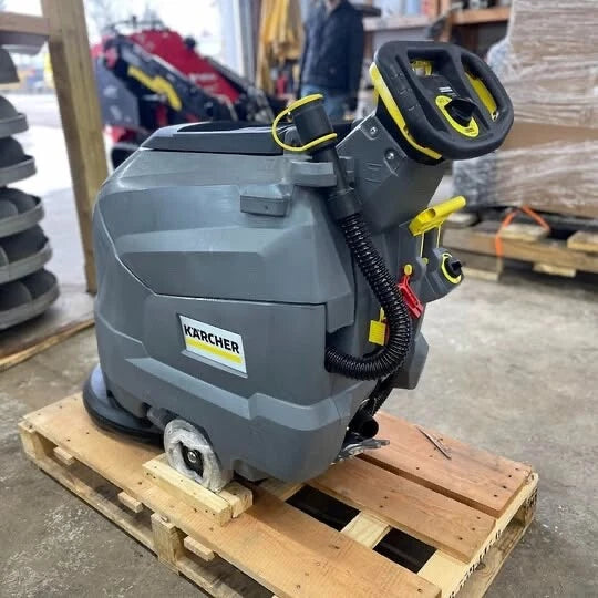 Angled front view of a Karcher BD 50/50 C Bp Classic floor scrubber with handle raised on a pallet